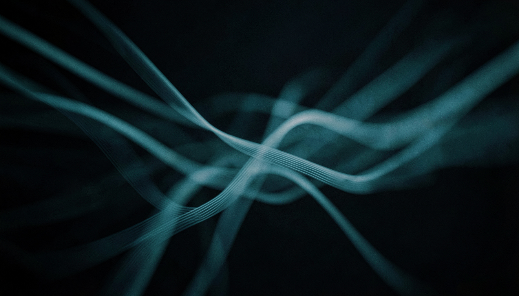 A cinematic wide frame with shallow depth of field showing abstract flowing data lines in muted teal and slate-blue against a dark background